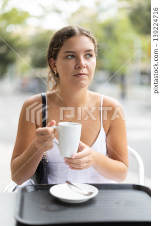 Young woman sitting in cafe and drinking tea Young woman sitting in cafe and drinking tea 139224716