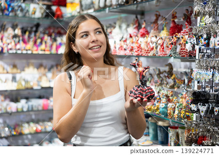 Female buyer holds in hands tests figurine she-dancer flamenco in memorable gifts shop Female buyer holds in hands tests figurine she-dancer flamenco in memorable gifts shop 139224771
