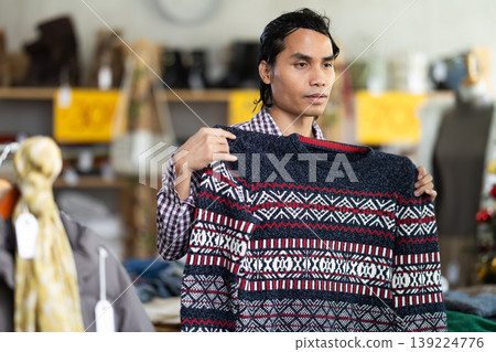 In chain shop, Indonesian man choose sweater In chain shop, Indonesian man choose sweater 139224776
