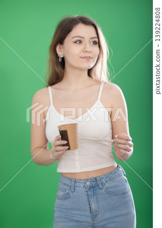 Young woman drinking coffee in front of green screen 139224808