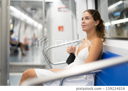 Pleased young girl sitting in wagon travelling by subway Pleased young girl sitting in wagon travelling by subway 139224816