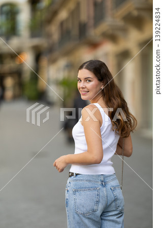 Girl turning with calm relaxed expression on sunny street 139224834