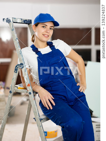 Smiling woman repairer at stepladder inside apartment Smiling woman repairer at stepladder inside apartment 139224837
