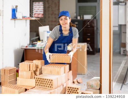 Female builder stacking bricks at construction site Female builder stacking bricks at construction site 139224910