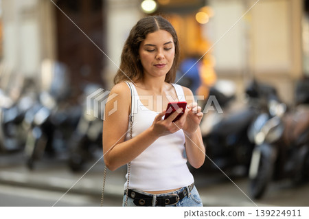 Girl looks at smartphone screen while walking Girl looks at smartphone screen while walking 139224911