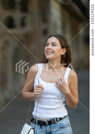 Young smiling girl walks along city street Young smiling girl walks along city street 139224928