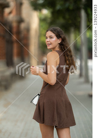 woman stands on the street with a phone in her hands and turns around woman stands on the street with a phone in her hands and turns around 139224933