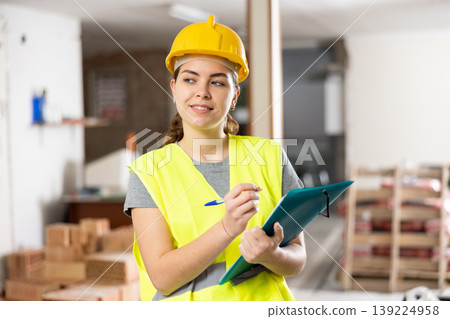 Smiling female civil engineer standing with papers at construction site Smiling female civil engineer standing with papers at construction site 139224958