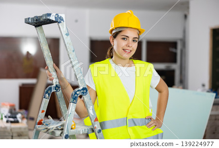 Portrait of female foreman in protective yellow vest and hard hat in room being renovated Portrait of female foreman in protective yellow vest and hard hat in room being renovated 139224977
