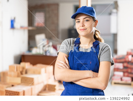 Portrait of positive woman builder standing in construction site 139224992