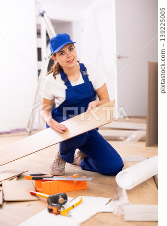Woman builder preparing laminated boards for laying floors Woman builder preparing laminated boards for laying floors 139225005