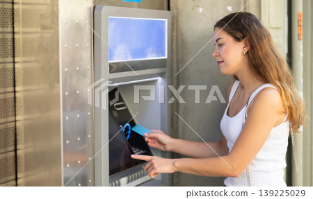 Girl uses ATM, withdraws cash from card Girl uses ATM, withdraws cash from card 139225029