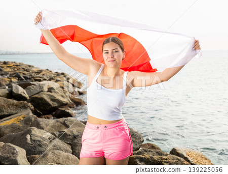 Young woman on coast posing with flag of Poland Young woman on coast posing with flag of Poland 139225056