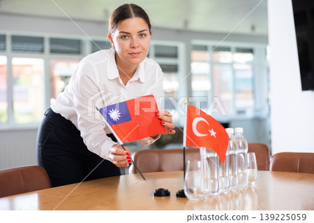 Positive young woman putting little flag of Taiwan on table next to the flag of Turkey Positive young woman putting little flag of Taiwan on table next to the flag of Turkey 139225059