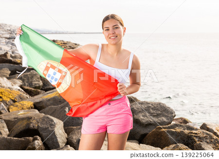 Young woman on coast posing with flag of Portugal Young woman on coast posing with flag of Portugal 139225064