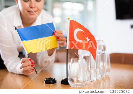 Little flag of Turkey on table and flag of Ukraine put next to it by young woman Little flag of Turkey on table and flag of Ukraine put next to it by young woman 139225082