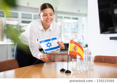 Young woman putting flags of Israel and Spain on table in office Young woman putting flags of Israel and Spain on table in office 139225088