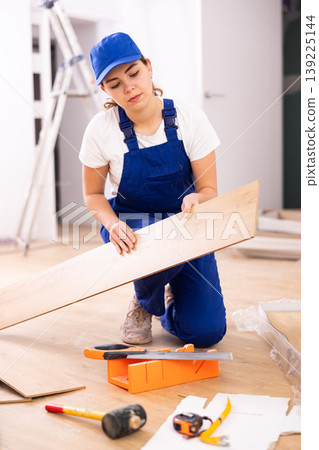 Female carpenter taking out laminate planks from package 139225144