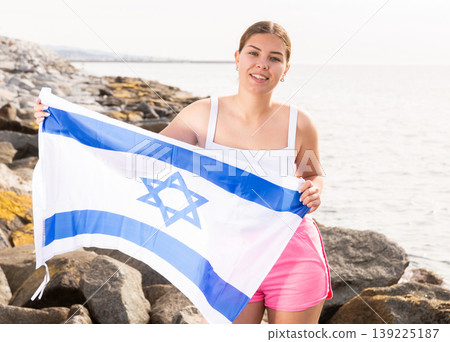 Young woman on coast posing with flag of Israel Young woman on coast posing with flag of Israel 139225187