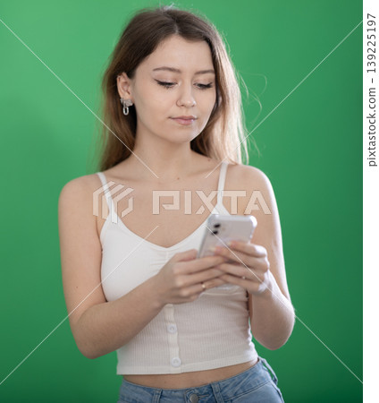 European woman using smartphone on green background European woman using smartphone on green background 139225197