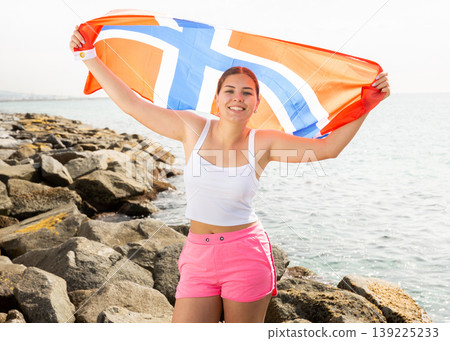 National flag of Norway. Beautiful woman with Norway flag on seashore National flag of Norway. Beautiful woman with Norway flag on seashore 139225233