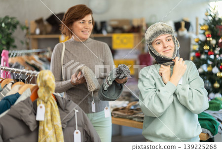 Mother with her teenage daughter choose warm hat together in fashionable clothing store 139225268