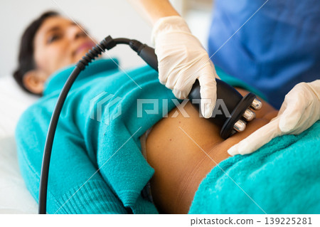 Woman receiving radio frequency abdomen lifting procedure Woman receiving radio frequency abdomen lifting procedure 139225281