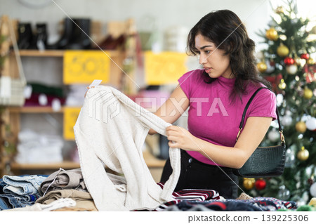 Asian woman chooses a sweater in clothing store before Christmas 139225306