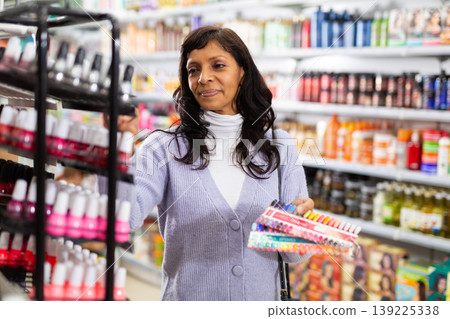 Latin American woman looking for nail varnish in cosmetic shop Latin American woman looking for nail varnish in cosmetic shop 139225338