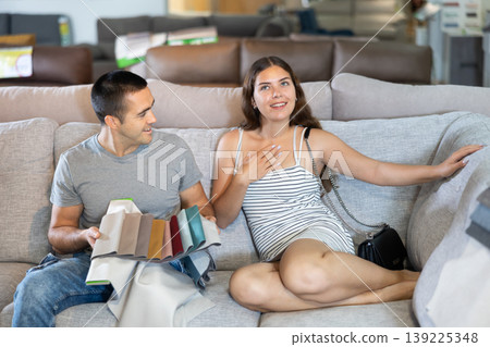 Smiling woman and man choosing upholstery for sofa in furnishing store Smiling woman and man choosing upholstery for sofa in furnishing store 139225348