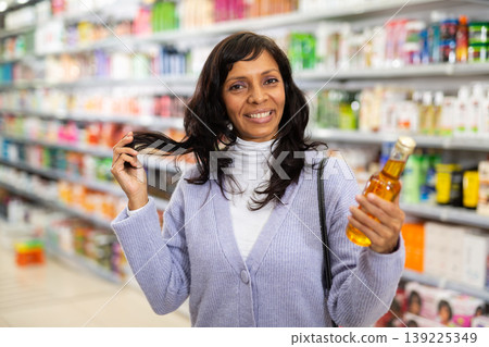 Woman buying new oil in hair care store Woman buying new oil in hair care store 139225349