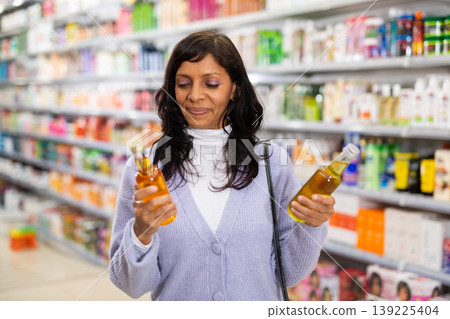 Adult Latina choosing haircare cosmetics in specialized boutique Adult Latina choosing haircare cosmetics in specialized boutique 139225404