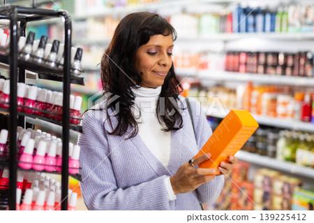Adult Latina choosing haircare cosmetics in specialized boutique 139225412