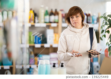 Attentive woman chooses cosmetics in supermarket Attentive woman chooses cosmetics in supermarket 139225449