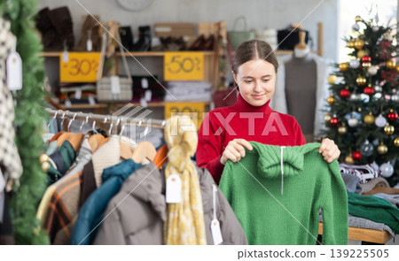 Teen girl picks up clothes and chooses sweater, New Year Eve sale Teen girl picks up clothes and chooses sweater, New Year Eve sale 139225505