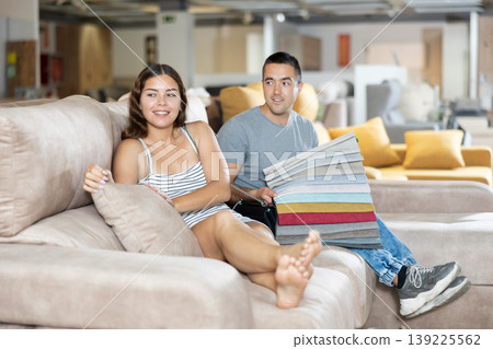 Man with his girlfriend are choosing modern materials for furniture for their home in furniture store Man with his girlfriend are choosing modern materials for furniture for their home in furniture store 139225562