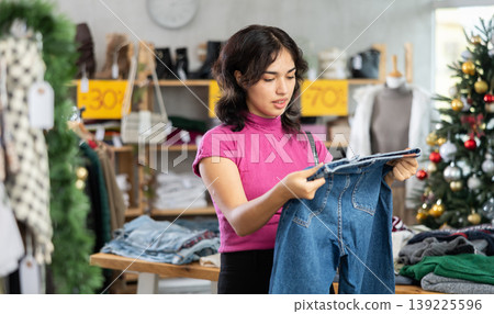 Asian woman chooses jeans trousers in clothing store before Christmas Asian woman chooses jeans trousers in clothing store before Christmas 139225596