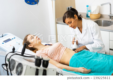 Doctor making rejuvenation electroporation procedure on abdomen 139225611