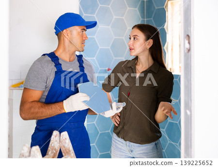 Female owner consults with a professional builder about installing a ceramic tile in remodeling Female owner consults with a professional builder about installing a ceramic tile in remodeling 139225652