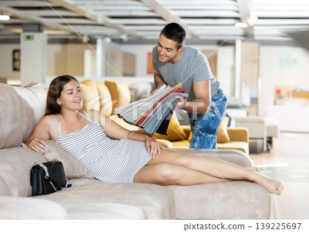 Man with his girlfriend are choosing modern materials for furniture for their home in furniture store Man with his girlfriend are choosing modern materials for furniture for their home in furniture store 139225697