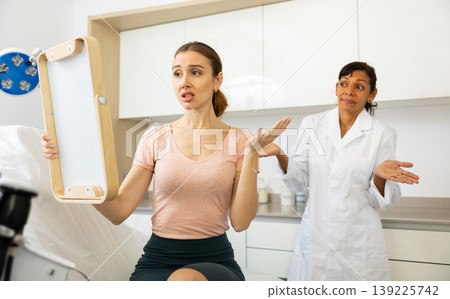 Dissatisfied woman checking result after cosmetology procedure Dissatisfied woman checking result after cosmetology procedure 139225742