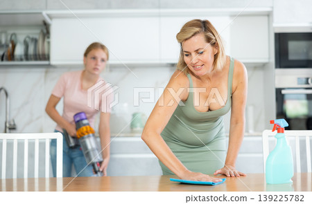 Woman engaged in household cleaning together with teenage daughter Woman engaged in household cleaning together with teenage daughter 139225782