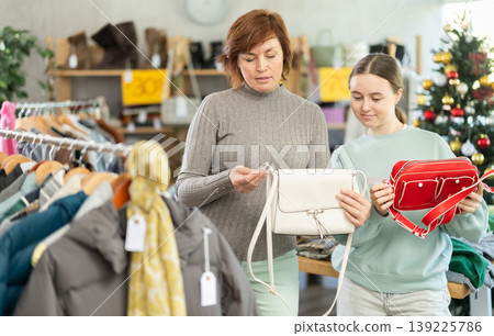 Teen girl with mum picks up clothes and choose handbag, New Year Eve sale Teen girl with mum picks up clothes and choose handbag, New Year Eve sale 139225786