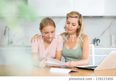 Cheerful woman with teenage daughter reading letter together Cheerful woman with teenage daughter reading letter together 139225800
