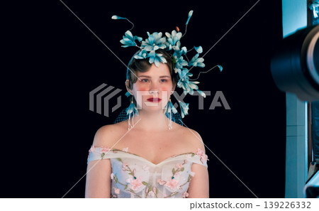 Young woman with an elaborate blue floral headpiece and embroidered dress posing in a professional studio setting Young woman with an elaborate blue floral headpiece and embroidered dress posing in a professional studio setting 139226332