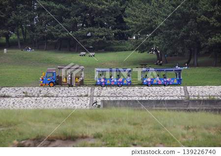 The park's streetcar makes a fun loop around the park. Everyone seems to be enjoying themselves, waving and cheering. The park's streetcar makes a fun loop around the park. Everyone seems to be enjoying themselves, waving and cheering. 139226740