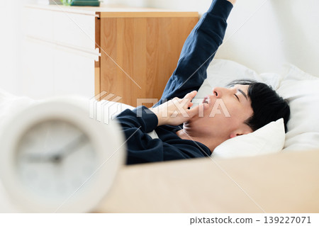 A young man oversleeps A young man oversleeps 139227071
