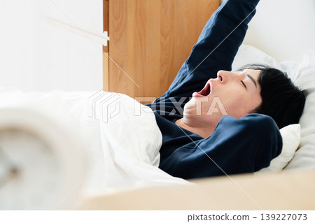 A young man oversleeps A young man oversleeps 139227073