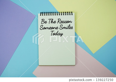 Be The Reason Someone Smiles Today text written on notepad flat lay on multicolor pastel background 139227250