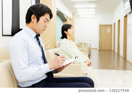 一位商人正在醫院候診室填寫醫療問卷。 一位商人正在醫院候診室填寫醫療問卷。 139227549